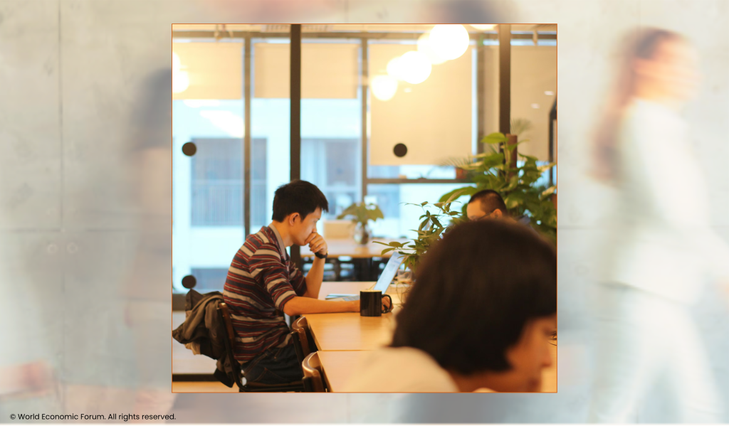 People working in a modern workplace. Glass. Natural light. Plants. Harvest tables and cubicles. (c) World Economic Forum. All rights reserved.